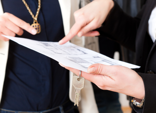Two people pointing at a written commercial lease document, with one set of hands holding keys.